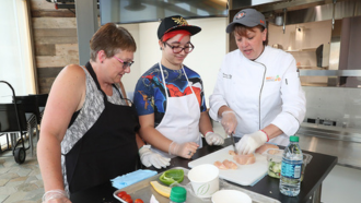 A chef teaching two people how to cook.