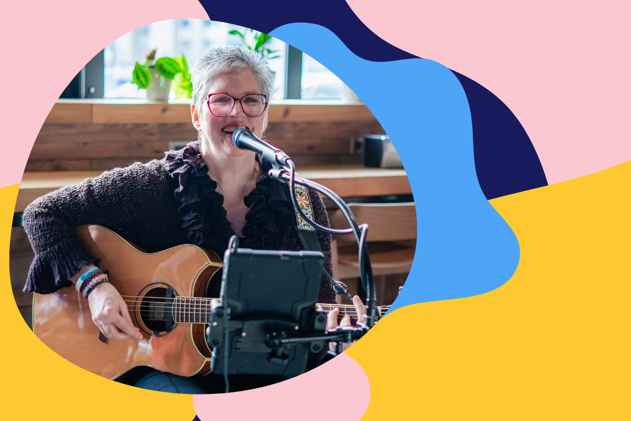 The Music Lady strumming a guitar while singing into a microphone.