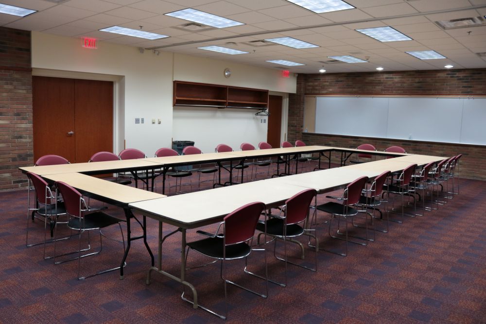 Tables and chairs set in a rectangle formation in a brightly lit room.